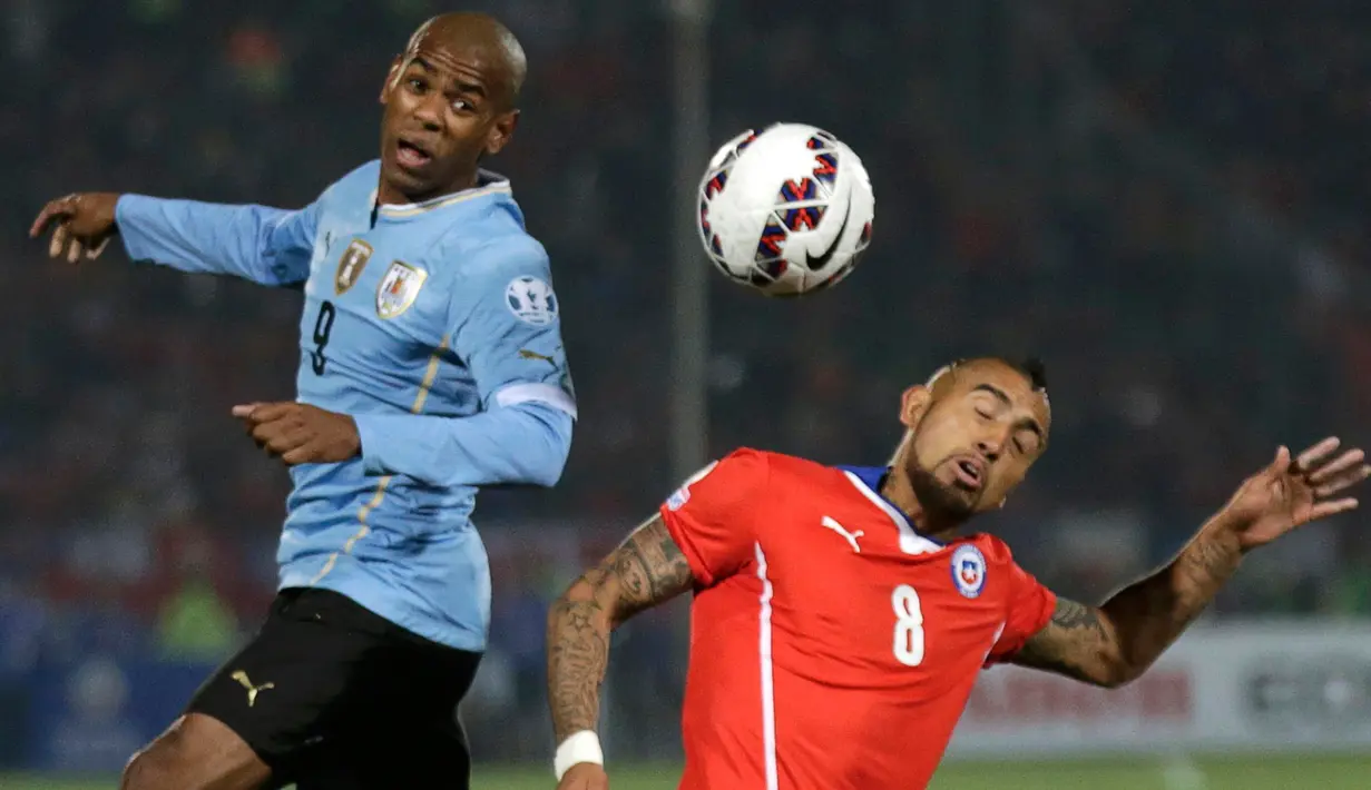 Gelandang Chile, Arturo Vidal (kanan) berebut bola udara dengan Penyerang Diego Rolan di perempat final Copa Amerika 2015 di National Stadium, Santiago, Chile, (25/6/2015). Chile melaju ke semifinal usai mengalahkan Uruguay 1-0. (REUTERS/Henry Romero)
