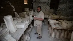 Salah seorang pengrajin Mostafa el-Agoury menyelesaikan pembuatan vas di provinsi Nil Delta Menoufiya, Mesir (21/6). (AFP/Mohamed el-Shahed)