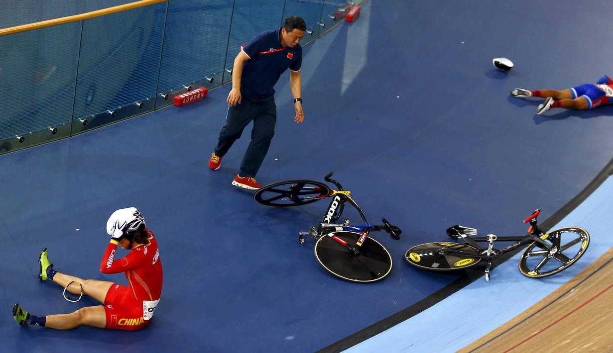 Seorang staff membantu dua pebalap yang bertabrakan yaitu Luo Xiao Ling , dari China (kiri) dan Marlies Mejias Garcia dari Kuba pada Kejuaraan UCI World Track Cycling Championships di London, Sabtu (5/3/2016). (REUTERS/Andrew Winning)   