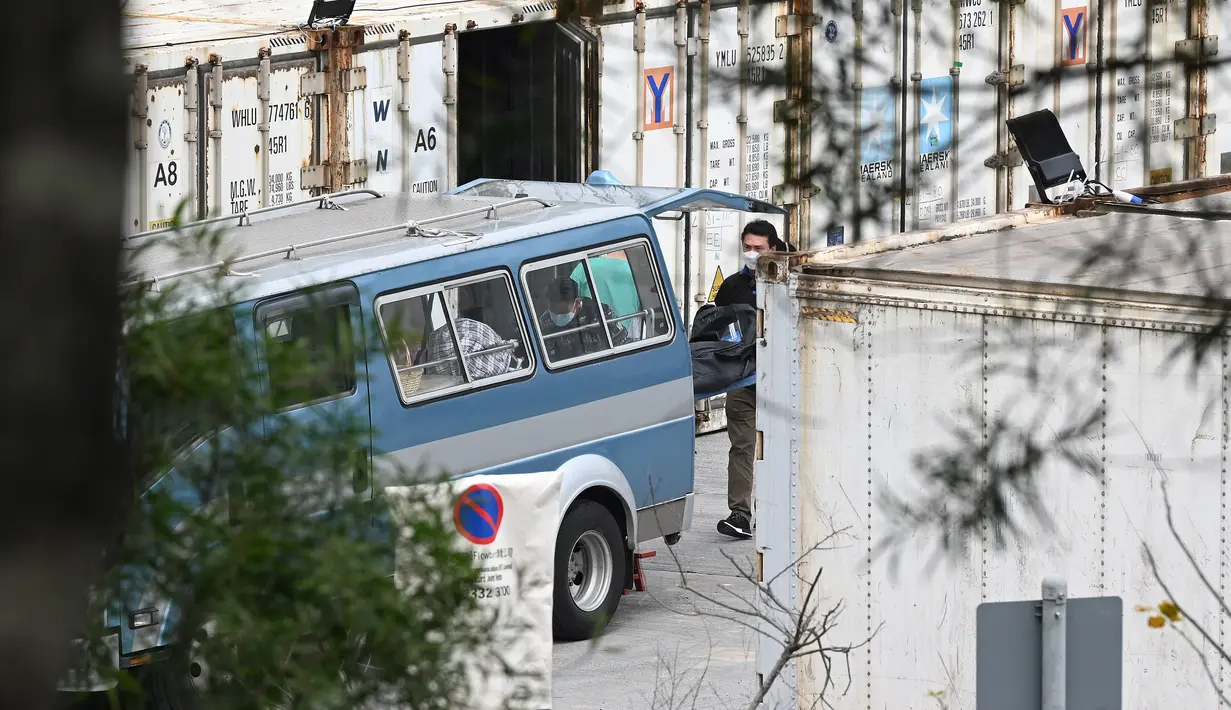 Pekerja memindahkan jenazah dari kontainer berpendingin ke mobil jenazah di Rumah Sakit Umum Fu Shan di Hong Kong (6/3/2022).  Penyebaran varian Omicron membuat tingkat kematian pasien Covid-19 di Hong Kong menjadi salah satu yang tertinggi di dunia. (AFP/Peter Parks)