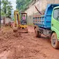 Ekskavator membersihkan sisa lumpur dan kayu di dekat Jembatan Desa Srigading, Lawang, Malang pada Rabu, 9 Maret 2022. Material itu terbawa banjir bandang yang menerjang Lawang satu hari sebelumnya (Zainul Arifin/Liputan6.com)