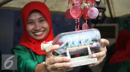 Seorang penjaga stan memperlihatkan barang dagangannya di acara palang pintu Lebaran Betawi di Lapangan Banteng, Jakarta (22/08/15). Acara ini akan berlangsung pada tanggal 22-23 Agustus. (Liputan6.com/Gempur M Surya)