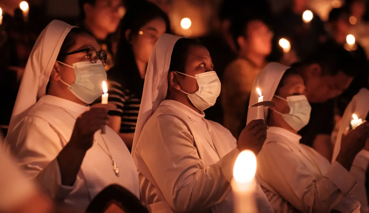 Umat Katolik memegang lilin saat Malam Paskah di gereja Santo Kristoforos di Jakarta pada 30 Maret 2024. (Yasuyoshi CHIBA/AFP)