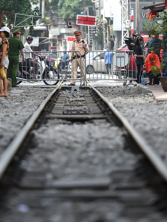 Polisi berjaga dekat barikade rel kereta yang populer sebagai lokasi selfie di Hanoi, Vietnam, Kamis (10/10/2019). Pihak berwenang menutup kafe-kafe di pinggir rel kereta tersebut sampai akhir pekan. (Nhac NGUYEN/AFP)