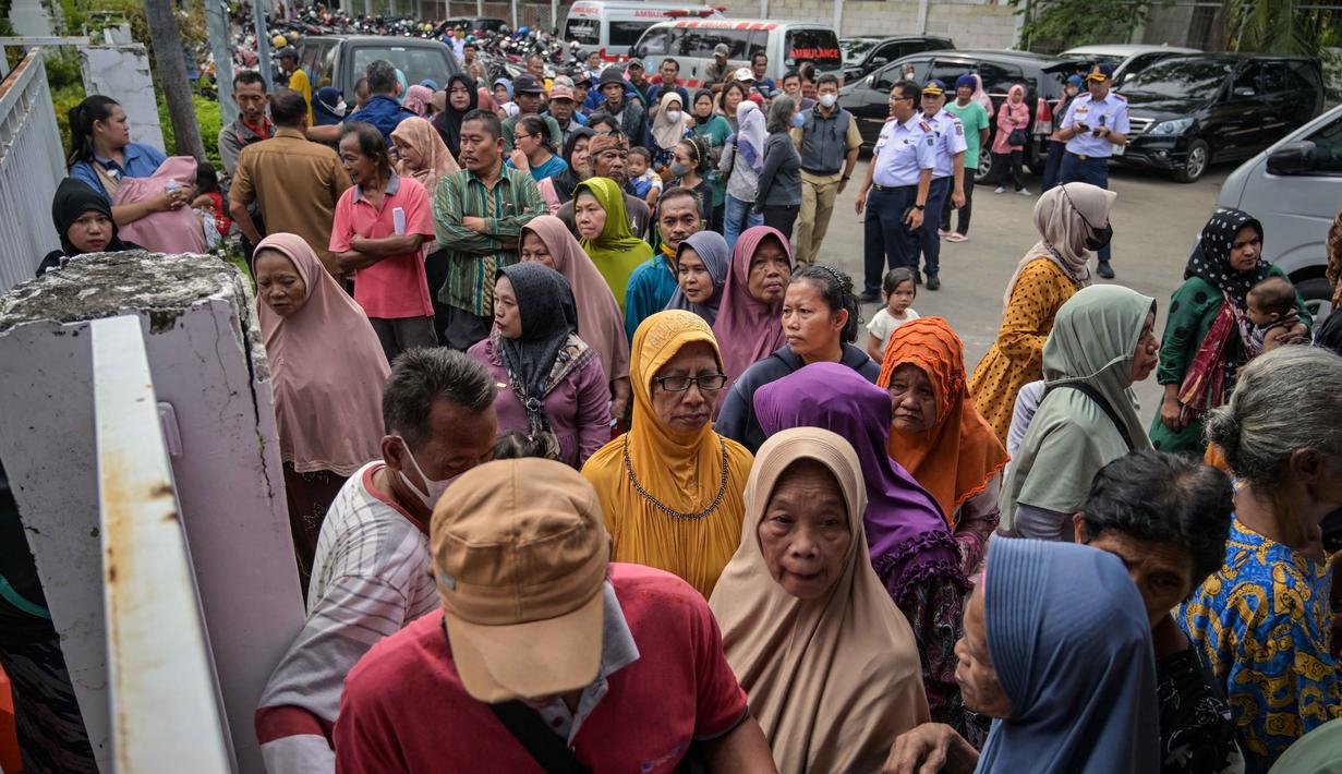 Orang-orang mengantre untuk menerima barang-barang gratis seperti pakaian, bahan makanan pokok, dan perlengkapan rumah tangga yang disediakan oleh Asosiasi Organisasi Wanita (GOW) dan pemerintah daerah selama acara aksi sosial tahunan di bulan Ramadan, Surabaya pada Senin 2 Maret 2026. (JUNI KRISWANTO/AFP)