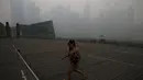 Seorang wanita berjalan melewati distrik pusat bisnis Singapura yang diselimuti kabut, Senin (14/9/2015). Singapura tak luput terkena dampak kabut asap pembakaran lahan di Pulau Sumatera. (REUTERS/Edgar Su)