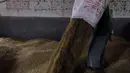 Pekerja menumpahkan gabah kering dari karung ke lantai saat proses penggilingan. (merdeka.com/Imam Buhori)
