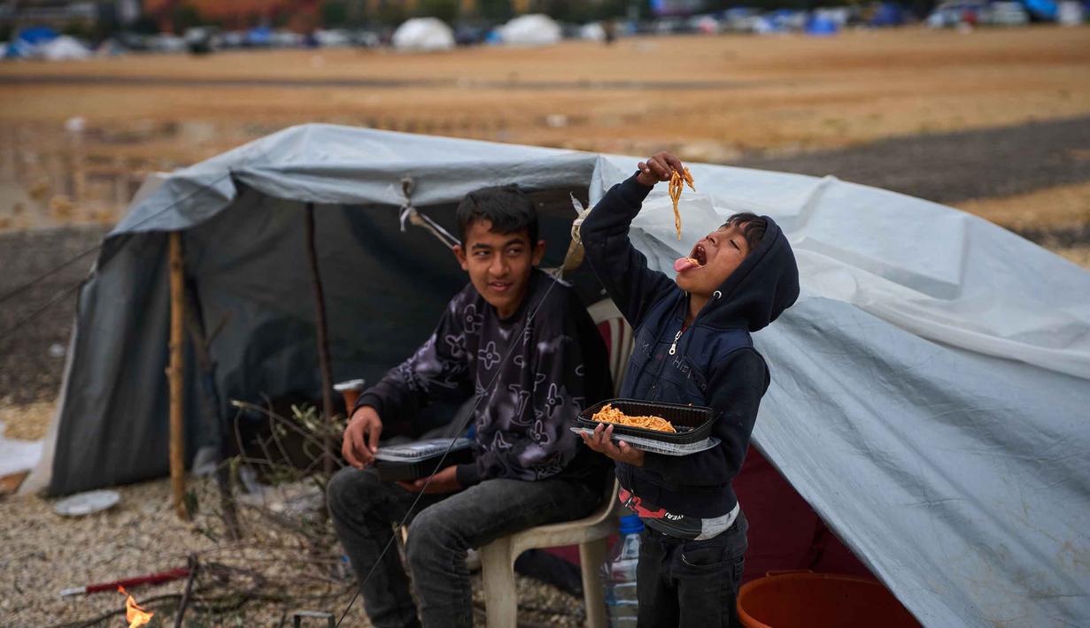 Mereka mencari perlindungan di perkemahan sementara yang serba terbatas. Tampak dalam foto, anak-anak pengungsi yang melarikan diri bersama keluarga mereka dari serangan Israel di Lebanon selatan memakan makanan sumbangan di samping tenda yang mereka gunakan sebagai tempat berlindung di Beirut, Lebanon, Rabu, 1 April 2026. (AP Photo/Emilio Morenatti)
