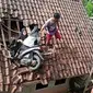 Dua remaja bersama sepeda motor yang mereka gunakan terjebak dipuing puing genteng rumah, sementara satu remaja putri lainya berada dibawah rumah warga, genteng rumah nampak hancur berantakan. (Liputan6.com/Jayadi Supriadin)