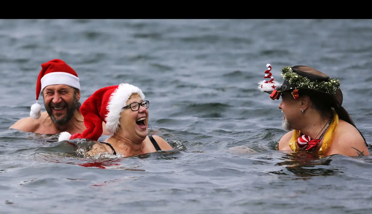 Puluhan anggota klub renang es "Berliner Seehunde" merayakan Natal dengan berenang di danau Orankesee, Berlin (25/12/2014). Tampak, beberapa anggota klub berenang di danau Orankesee, Berlin. (REUTERS/Fabrizio Bensch)