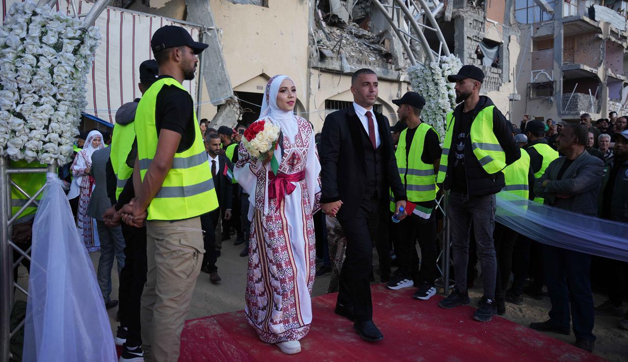 Peristiwa ini menghadirkan secercah kegembiraan di tengah situasi kemanusiaan yang penuh tekanan. Tampak dalam foto, pasangan Palestina berpartisipasi dalam upacara pernikahan massal di Kota Hamad, Khan Younis, Jalur Gaza, Selasa 2 Desember 2025. (AP Photo/Abdel Kareem Hana)