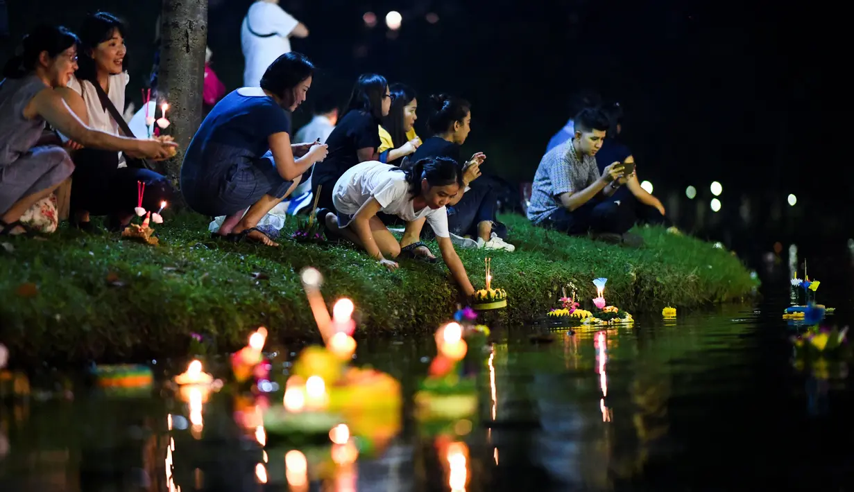 Orang-orang Thailand menghayutkan 'krathong' untuk merayakan festival Loy Krathong di sebuah danau di Bangkok, Kamis (22/11). Festival ini biasanya berlangsung pada akhir musim hujan, ketika bulan purnama menyala di langit pada November. (Jewel SAMAD/AFP)