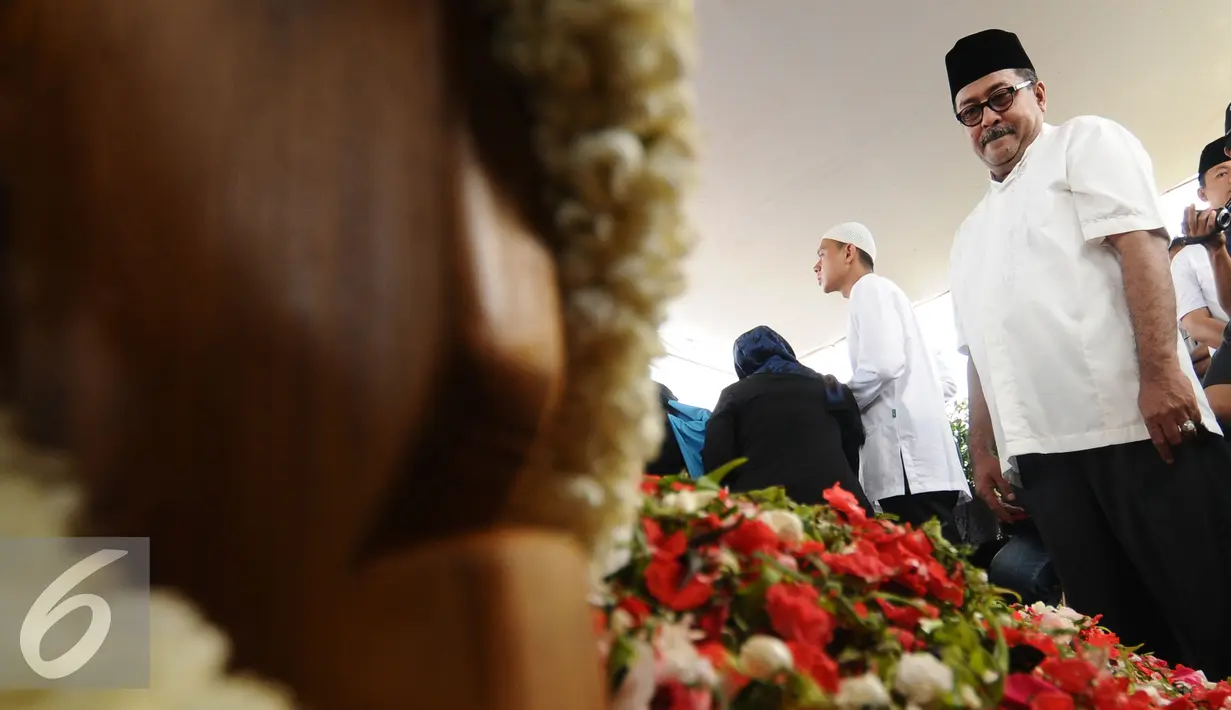 Gubernur Banten, Rano Karno menatap makam ibunya, Lily Soekarno M Noor di TPU Tanah Kusir Jakarta, Senin (7/12/2015). Ibunda Rano Karno wafat di usia 77 tahun akibat komplikasi penyakit. (Liputan6.com/Helmi Fithriansyah)