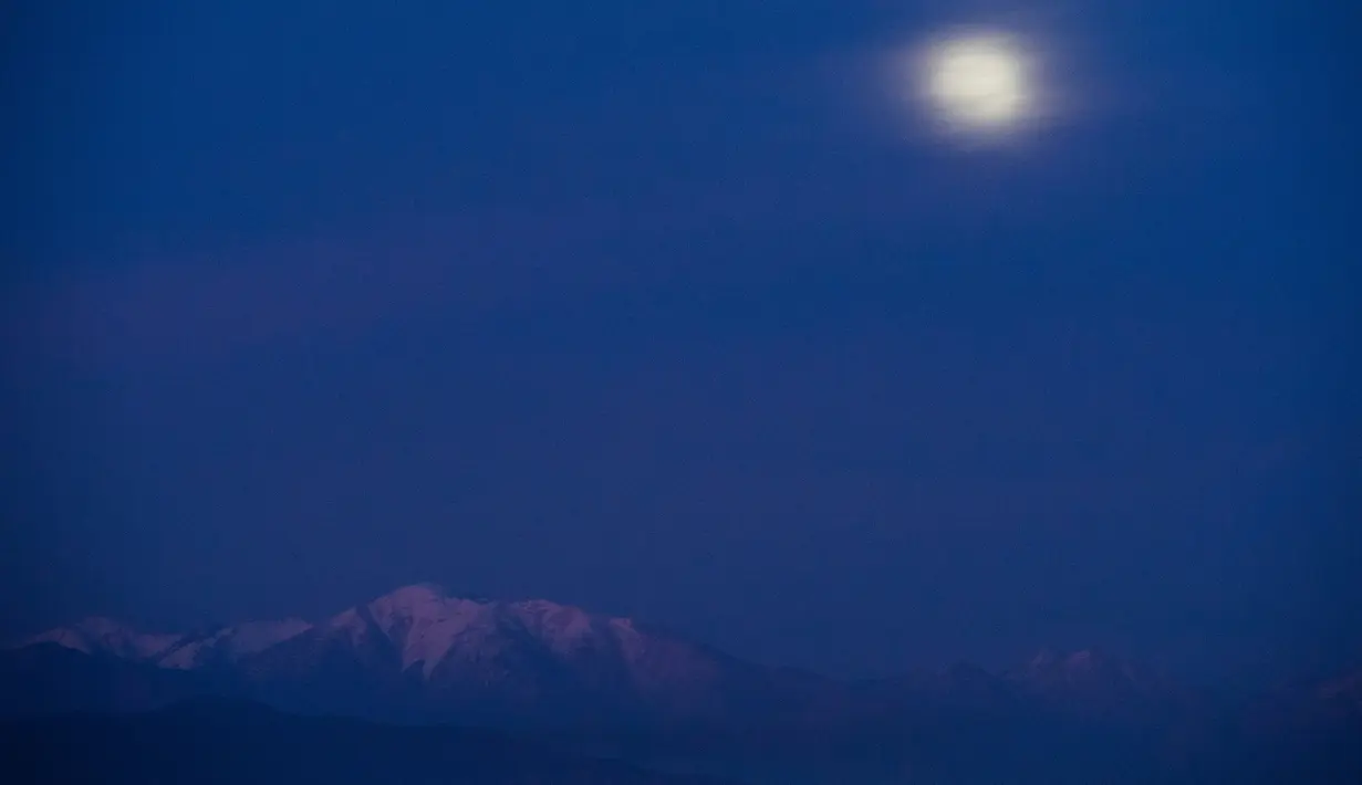 Fenomena supermoon yang sebagaian tertutup awan terlihat di atas Hutan Nasional Angeles, Los Angeles, Minggu (20/1). Supermoon terlihat dari sejumlah wilayah Amerika Utara dan Selatan, Eropa, dan Afrika Barat. (Robyn Beck / AFP)