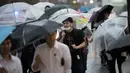 Seorang pria menggunakan payung berjalan saat hujan turun di Tokyo, Jepang (8/8). Sejumlah maskapai membatalkan penerbangan akibat cuaca yang kurang mendukung. (AFP Photo/Behrouz)