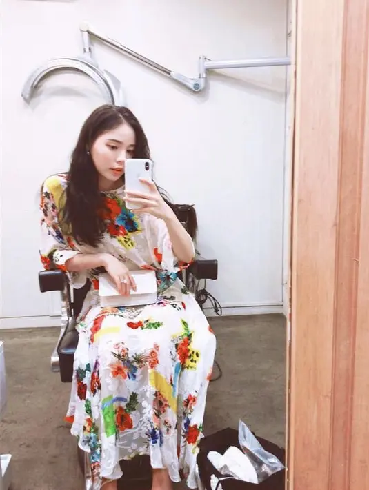 Long dress putih bermotif bunga colorful dikenakan Min Hyo Rin, tas putih melengkapi penampilannya. Dengan rambut panjang yang dibiarkan terurai. Instagram @hyorin_min