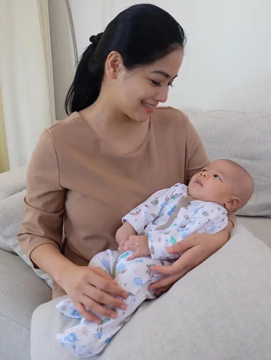 Titi memang tidak berlebihan saat berpenampilan. Namun, ia selalu berhasil memancarkan aura keibuannya yang cantik jelita. Seperti ini misalnya, penampilan Titi begitu sederhana saat menggendong baby Kai Attar Sugiono. (Instagram/titi_kamall)