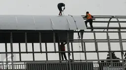 Pekerja melakukan pemasangan atap Jembatan Penyebrangan Orang (JPO) di Jalan Kasblanca, Jakarta, Selasa (22/11). Pemerintah Provinsi DKI Jakarta menargetkan perbaikan JPO tak layak segera rampung. (Liputan6.com/Helmi Fithriansyah)