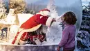 Seseorang yang berpakaian seperti Sinterklas yang berada dalam bola salju seukuran aslinya bertemu dengan anak-anak saat membuka musim Natal di Kebun Binatang Aalborg, di tengah krisis virus corona yang berlanjut, di Aalborg, Denmark pada Jumat (13/11/2020). (Henning Bagger / Ritzau Scanpix / AFP)