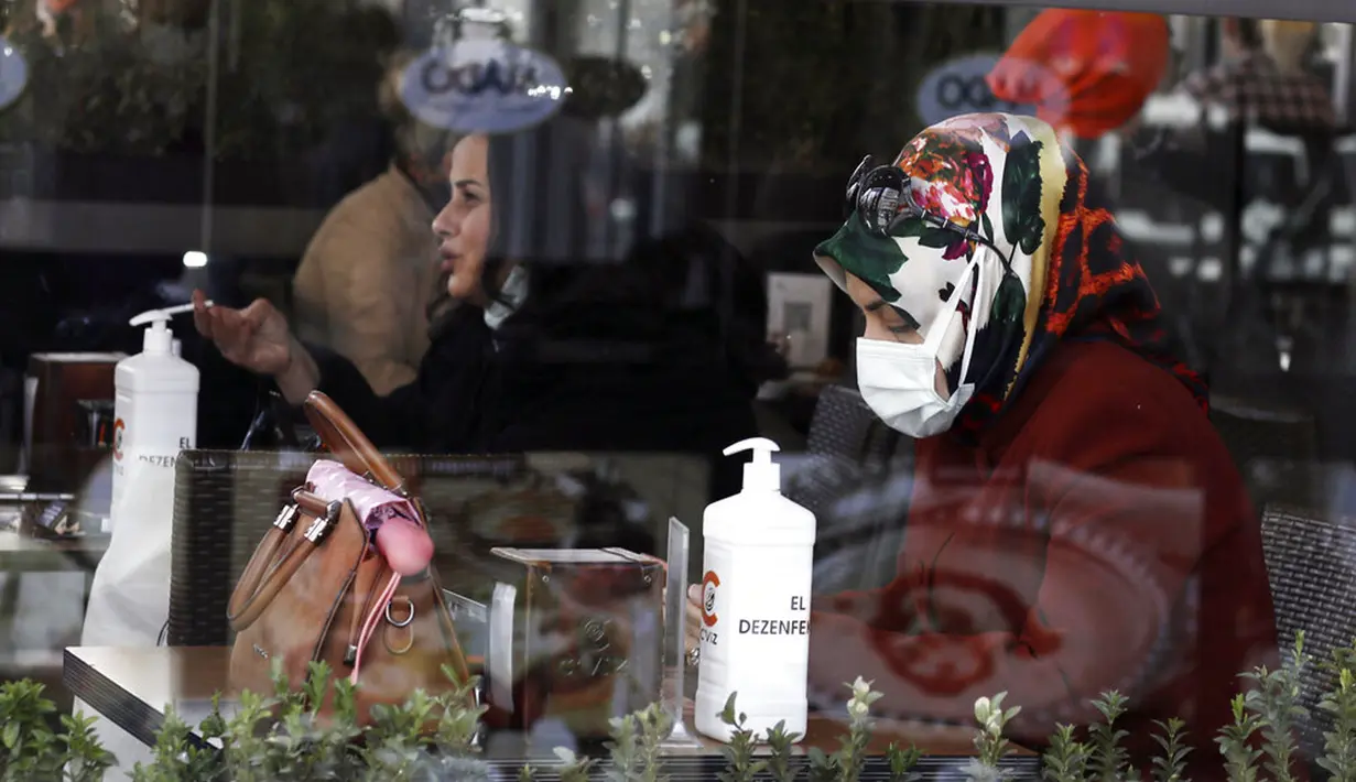 Seorang wanita yang mengenakan masker untuk membantu melindungi dari penyebaran COVID-19 duduk dalam kafe di Ankara, Turki, Selasa (30/3/2021). Turki kembali memberlakukan lockdown akhir pekan dan pembatasan selama Ramadan menyusul peningkatan tajam kasus COVID-19. (AP Photo/Burhan Ozbilici)
