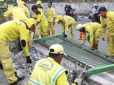 Petugas Dinas Bina Marga membongkar pagar dan sepatator di Jalan Galunggung, Jakarta, Kamis (10/1). Pembongkaran dilakukan guna menghilangkan batas antar jalur sehingga diharapkan dapat mengurai simpul kemacetan. (Liputan6.com/Immanuel Antonius)