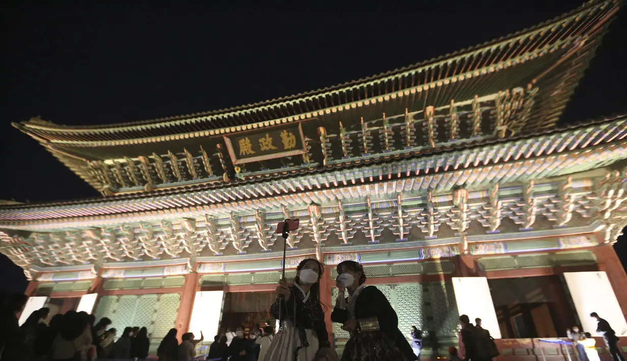Wanita yang mengenakan masker berswafoto selama Festival Budaya Kerajaan di Istana Gyeongbok, Seoul, Korea Selatan, Rabu (14/10/2020). Festival warisan budaya selama sebulan yang mengeksplorasi istana dan budaya kerajaan Korea Selatan dimulai pada 10 Oktober 2020. (AP Photo/Ahn Young-joon)