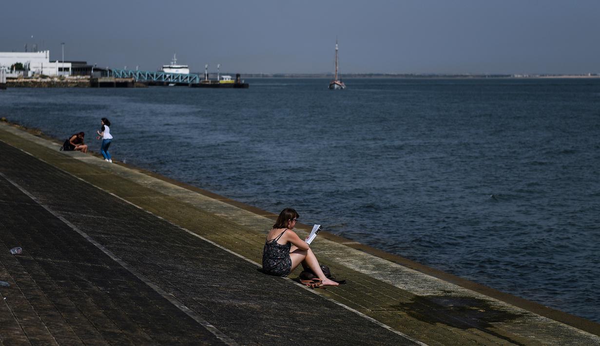 Seorang wanita membaca buku di Ribeira das Naus, Lisbon (3/8). Suhu tertinggi tercatat di Eropa adalah 48 derajat di Athena tahun 1977, diikuti 47,3 di Amareleja, Portugal 2003 serta di Montoro, Spanyol tahun lalu. (AFP Photo/Patricia De Melo Moreira)