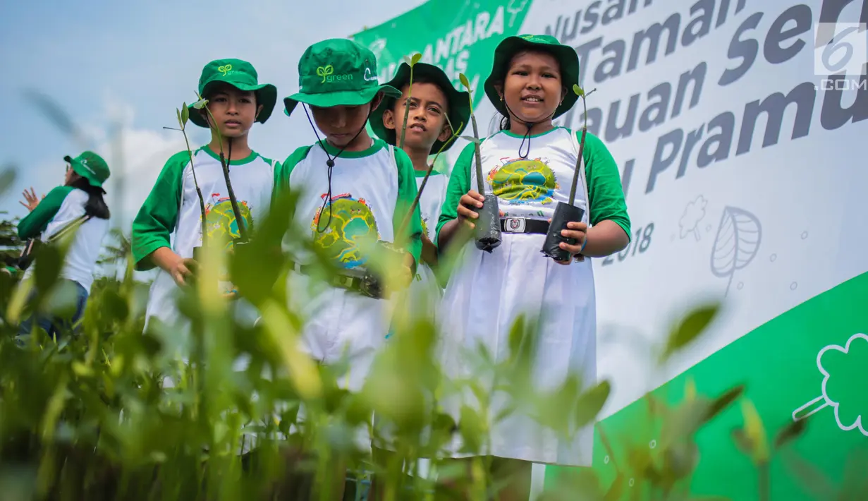 Siswa sekolah dasar memperlihatkan tanaman mangrove saat mengikuti kegiatan menanam 100.000 pohon di Area Labirin Pulau Pramuka, Kepulauan Seribu, Jakarta, Rabu (28/11). (Liputan6.com/Faizal Fanani)