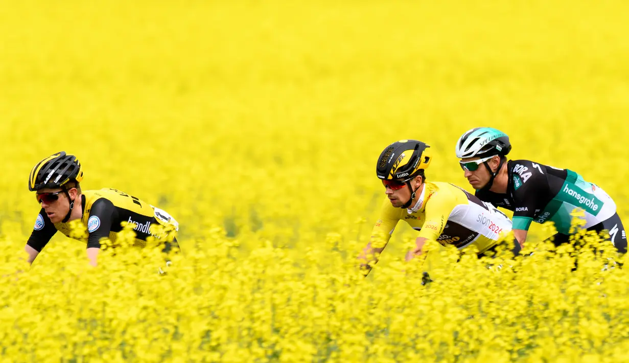 Tiga pembalap sepeda melintas di ladang rapeseed dengan hamparan bunga kuning yang cerah saat mengikuti perlombaan Tour de Romandie UCI ProTour ke-72 di Bottens, Swiss (29/4). (Laurent Gillieron / Keystone via AP)