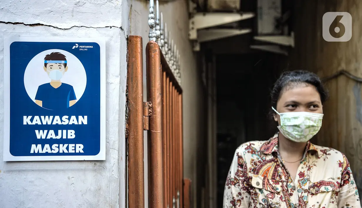 Warga saat berada di dekat papan imbauan mengenakan masker di Kampung Sehat, Utan Kayu Selatan, Jakarta, Rabu (11/11/2020). (merdeka.com/Iqbal S. Nugroho)
