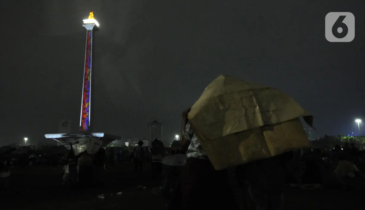 Pengunjung menyaksikan penampilan video mapping saat malam pergantian tahun di kawasan Monumen Nasional, Jakarta, Selasa (31/12/2019). Penampilan video mapping mewarnai kemeriahan malam pergantian tahun baru di kawasan Monumen Nasional, Jakarta. (Liputan6.com/Helmi Fithriansyah)