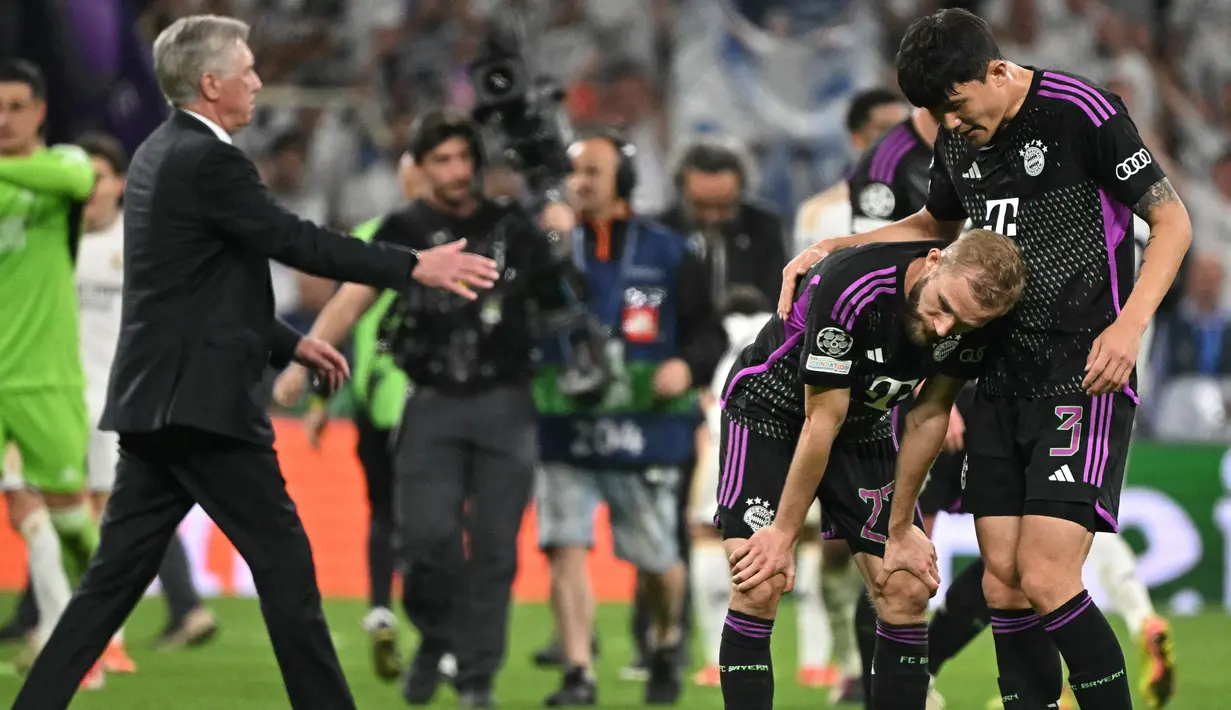 Pemain Bayern Munchen, Kim Min-jae (kanan) menenangkan Konrad Laimer yang tertunduk lesu setelah dikalahkan Real Madrid dalam laga leg kedua semifinal Liga Champions 2023/2024 di Santiago Bernabeu, Madrid, Spanyol, Kamis (09/05/2024) WIB. (AFP/Javier Soriano)