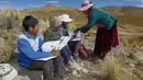 Raymunda Charca membantu anak-anaknya saat menghadiri kelas virtual selama pandemi COVID-19 di atas bukit di komunitas dataran tinggi Conaviri yang terpencil di Andes Peru, 24 Juli 2020. Mereka harus naik ke puncak bukit untuk mencari sinyal ponsel untuk menghadiri kelas virtual. (Carlos MAMANI/AFP)