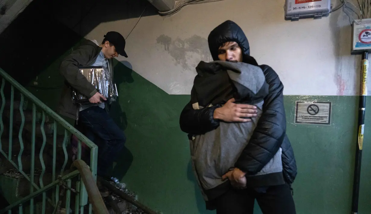 Penduduk setempat membawa barang-barang mereka dari sebuah bangunan tempat tinggal yang rusak menyusul serangan rudal Rusia di Kyiv, Ukraina, Senin 15 Juni 2026, di tengah invasi Rusia. (OLEKSII FILIPPOV/AFP)