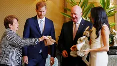 Pangeran Harry dan Meghan Markle bereaksi ketika menerima hadiah dari Gubernur Jenderal Australia Sir Peter Cosgrove dan istrinya, Lady Cosgrove di Sydney, Selasa (16/10). Meghan tampak senang menerima hadiah bayi pertamanya. (Phil Noble/Pool via AP)