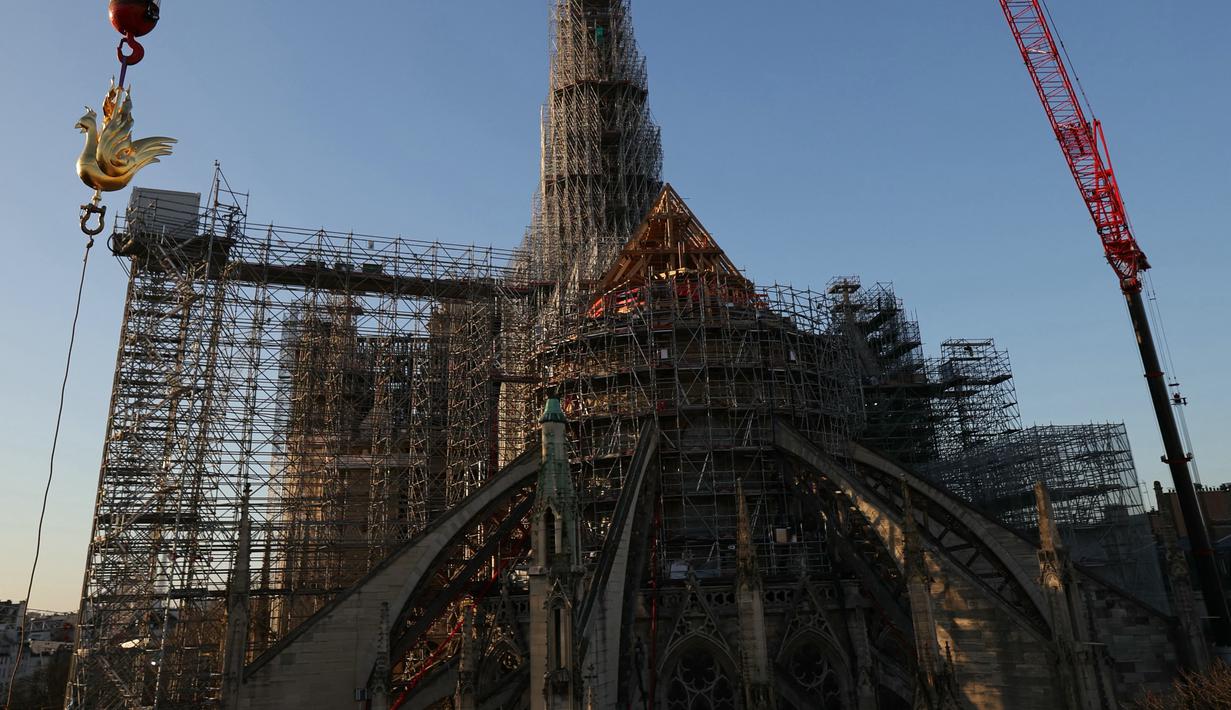Ayam jago emas baru berisi relik diangkat dengan derek untuk dipasang di puncak menara Katedral Notre Dame sebagai bagian dari rekonstruksi, di pusat kota Paris, Sabtu (16/12/2023). (Thomas SAMSON / AFP)