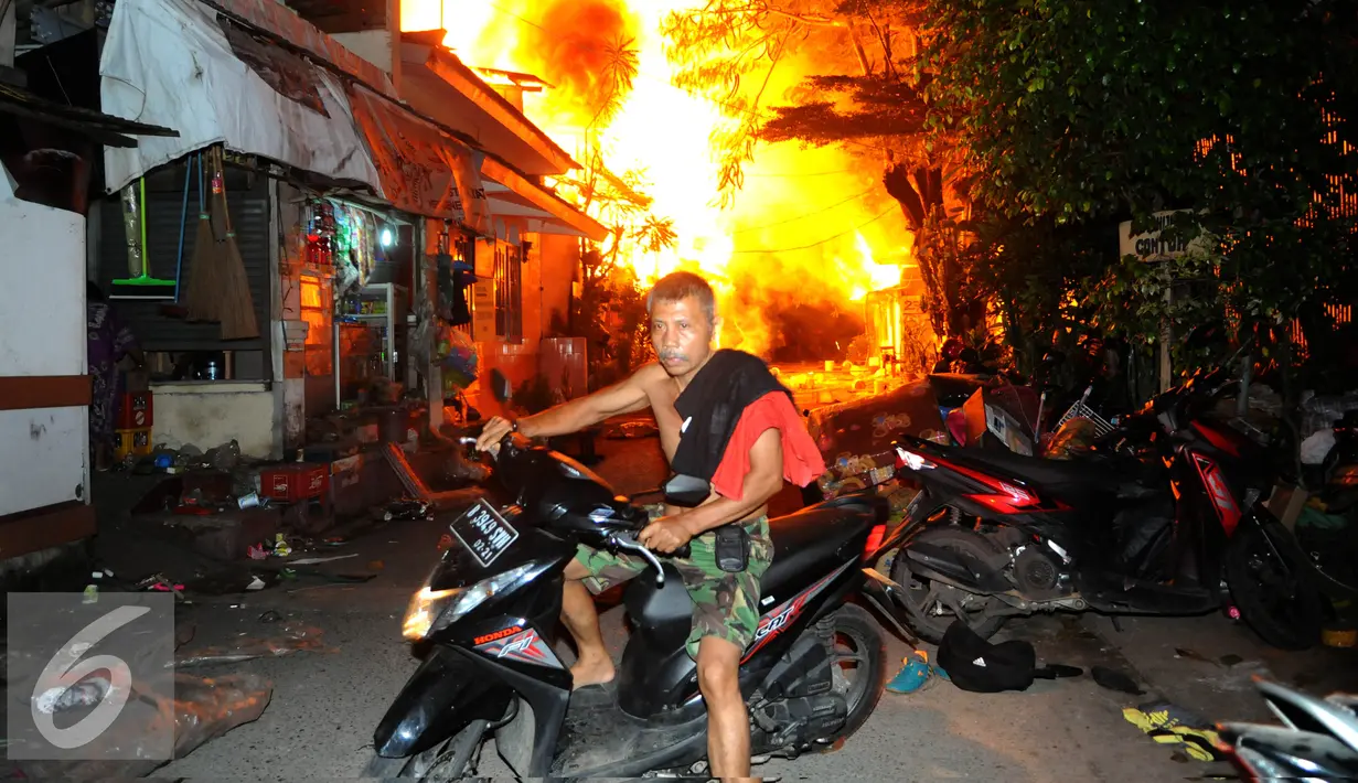 Seorang warga menyelamatkan diri dari kebakaran yang terjadi di belakang Senayan City, Jakarta, Minggu (3/7) dini hari. Sejumlah rumah semi permanen terbakar 38 mobil pemadam kebakaran dikerahkan. (Liputan6.com/Helmi Afandi)