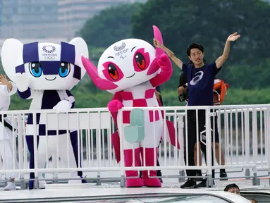 Maskot Olimpiade dan Paralimpik Tokyo 2020, Miraitowa (kiri) dan Someity (kanan) melambaikan tangan saat menaiki perahu di Rainbow Bridge, Tokyo, Jepang, Minggu (22/7). Miraitowa dan Someity resmi diperkenalkan kepada publik. (AP Photo/Eugene Hoshiko)