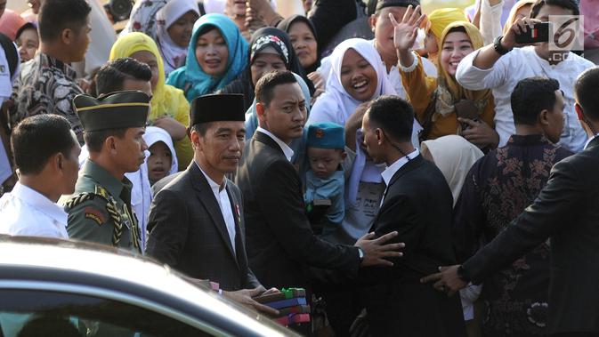 Presiden Joko Widodo atau Jokowi menyerahkan  buku kepada warga  usai  menunaikan salat Idul Adha 1439 Hijriah di Lapangan Tegar Beriman, Cibinong, Kabupaten Bogor, Jawa Barat, Rabu (22/08). (Merdeka.com/Arie Basuki)