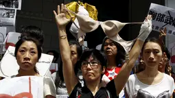 Pengunjuk rasa memegang bra di luar markas polisi di kawasan Wan Chai, Hong Kong, Minggu (2/8). Demo tersebut merupakan aksi simpati terhadap seorang perempuan yang di penjara karena dituduh menyerang polisi menggunakan payudaranya. (REUTERS/Tyrone Siu)