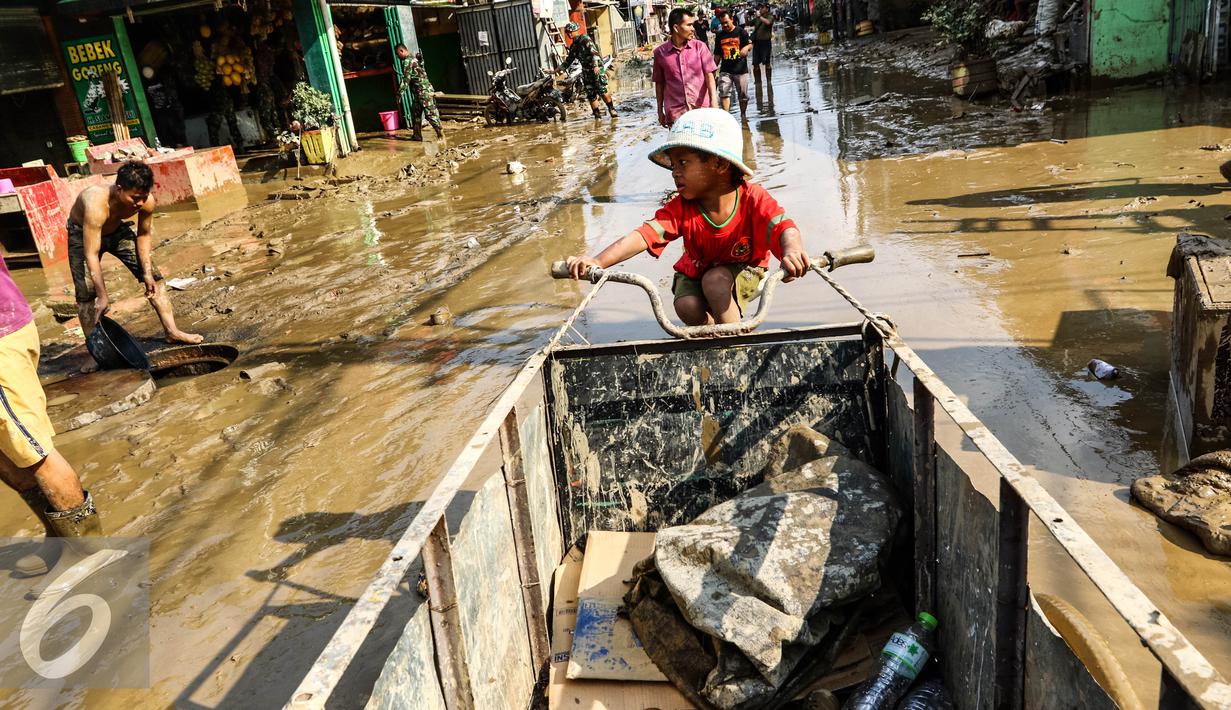 Seorang anak kecil terlihat duduk di gerobak barang bekas di komplek Pondok Gede Permai Jatiasih, Bekasi, Jumat (22/04). Tumpukan sampah akibat banjir menjadi rezeki tambahan bagi pemulung. (Liputan6.com/Fery Pradolo)