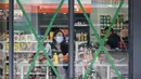 Orang-orang berbelanja di sebuah minimarket dengan jendela yang ditutup rapat saat Topan Super Ragasa mendekati Zhuhai, Provinsi Guangdong, Tiongkok Selatan, pada Selasa 23 September 2025. (Adek BERRY/AFP)
