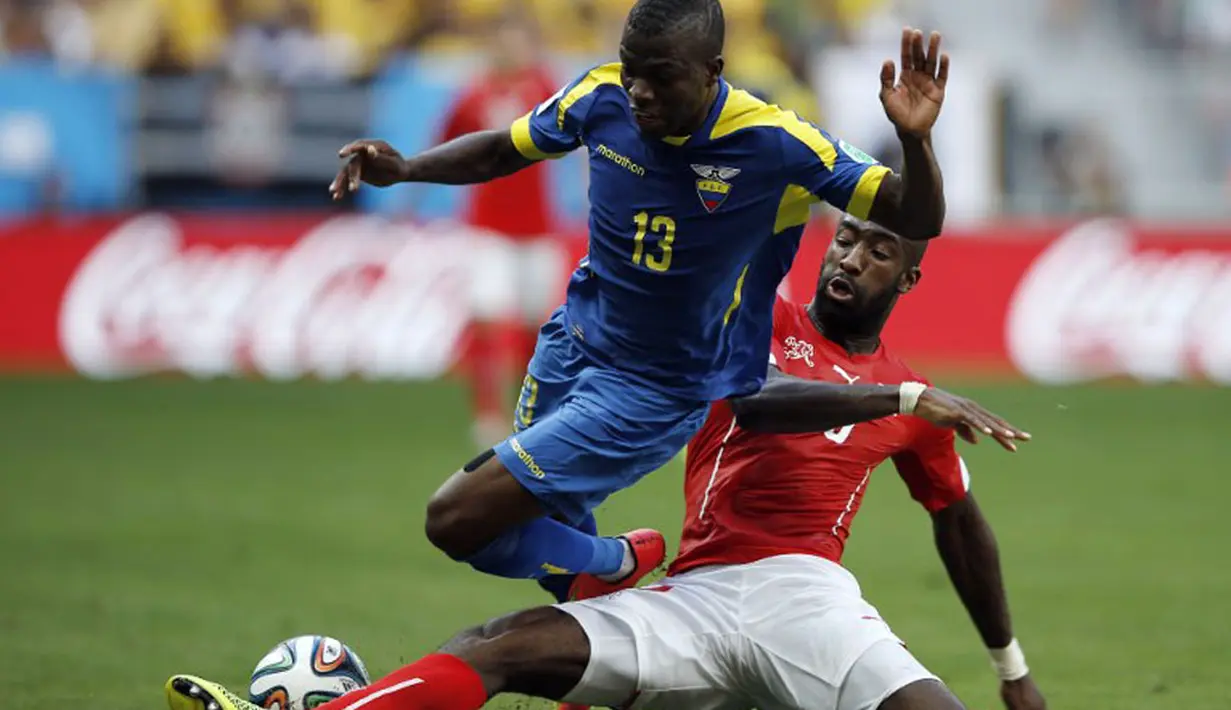 Laga Swiss kontra Ekuador berlangsung ketat. Pemain belakang Swiss, Johan Djourou (kanan) berusaha menahan serangan Enner Valencia (Ekuador) di laga penyisihan Piala Dunia 2014 Grup E di Estádio Nacional de Brasilia, (15/6/2014). (AFP PHOTO/Adrian Dennis)