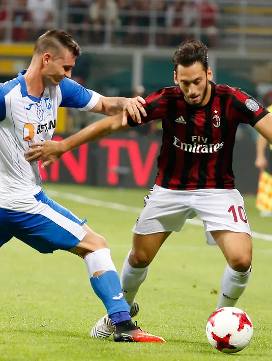 Gelandang AC Milan, Hakan Calhanoglu berusaha membawa bola dari kawalan pemain U Craiova, Hrvoje Spahija saat bertanding di leg kedua babak 3 Liga Europa di San Siro, Milan, (3/8). AC Milan sukses menang 2-0 atas Craiova. (AP Photo/Antonio Calanni)