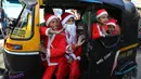 Anak-anak India mengenakan kostum Santa Claus menaiki Bajaj saat merayakan Natal di Jammu, India (22/12). Meskipun di India orang Kristen hanya 2 persen dari populasi, Natal di India cukup meriah. (AP Photo / Channi Anand)