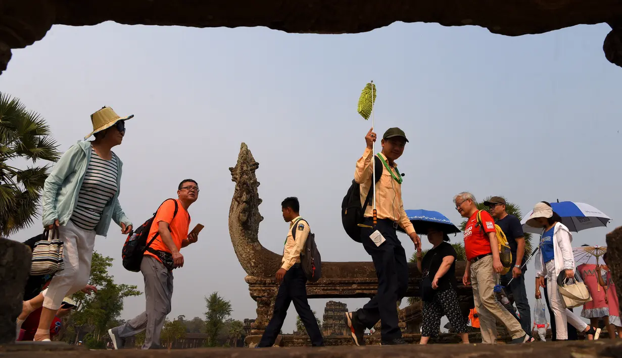 Turis mengunjungi candi Angkor Wat di provinsi Siem Reap, barat laut Kamboja pada 16 Maret 2019. Pada tahun 1992, Angkor Wat masuk ke dalam daftar Situs Warisan Dunia UNESCO. (TANG CHHIN Sothy / AFP)