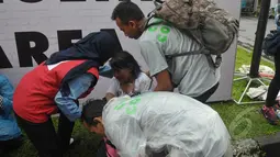 Petugas mengamankan seorang wanita yang pingsan saat mengantre untuk menonton konser One Direction, Senayan, Jakarta, Rabu (25/3/2015). Puluhan ribu orang rela mengantre untuk melihat konser One Direction. (Liputan6.com/Johan Tallo)