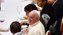 Paus Fransiskus duduk di sebuah meja dalam jamuan makan siang di Aula Paul VI, Vatikan, Minggu (17/11/2019). Paus Fransiskus mengundang sekitar 1.500 orang miskin, tunawisma, imigran dan pengangguran untuk makan siang dalam memperingati Hari Orang Miskin Sedunia. (Vincenzo PINTO / AFP)