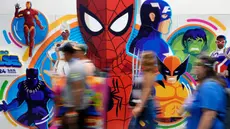 Para peserta konvensi melintasi dinding bergambar karakter superhero Marvel saat malam pratinjau Comic-Con International, Rabu, 24 Juli 2024, di San Diego. (AP Photo/Chris Pizzello)