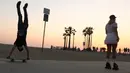 Seorang perempuan mengenakan sepatu roda di dekat pemain skateboard di sepanjang Venice Beach di Venice, California, Kamis (3/9/2020). Permintaan sepatu roda di Amerika Serikat mengalami peningkatan tajam di tengah pembatasan sosial akibat corona Covid-19. (Mario Tama/Getty Images/AFP)
